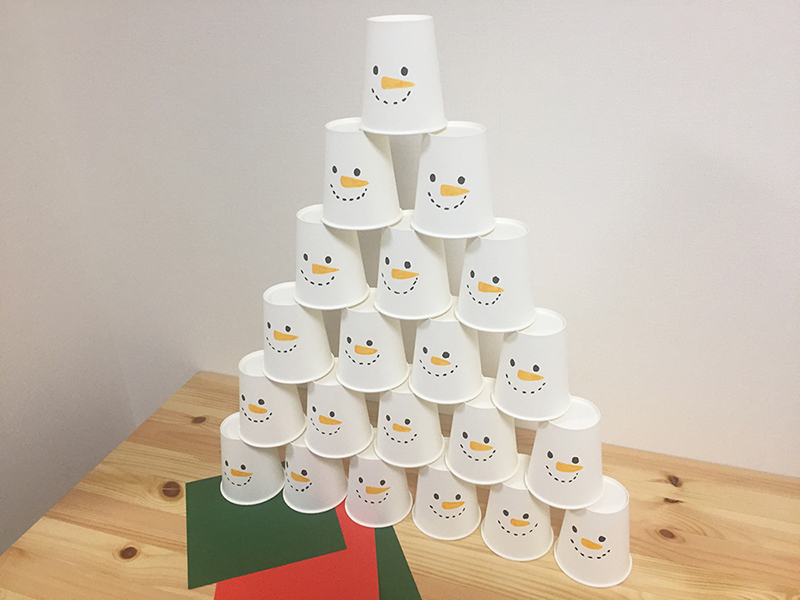 白い紙コップに雪だるまの顔おデザインして積み上げた紙コップタワー
